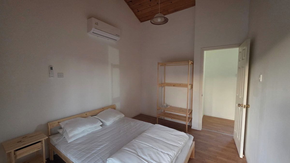 A bedroom with a wooden bed, a wooden ladder, a white door, and a ceiling fan.