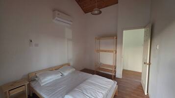 A bedroom with a wooden bed, a wooden ladder, a white door, and a ceiling fan.