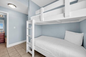 Ein Schlafraum mit Etagenbett, weißer Sprosse, weißer Matratze und weißem Kopfkissen.