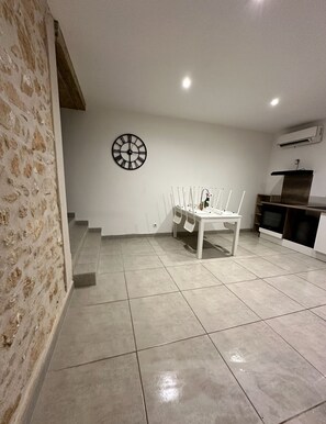 Ein geräumiges Zimmer mit einem Esstisch, Stühlen, einer Wanduhr und einer Treppe zu einer weiteren Ebene.