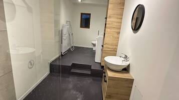 A modern bathroom with a glass shower enclosure, a white sink, and a wooden vanity.