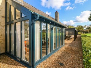 A conservatory with a gravel path leading to a seating area. - The Coach House at Gileston Manor (Barry)