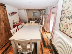 A dining area with a long table, chairs, and a rustic wooden floor. - The Coach House at Gileston Manor (Barry)