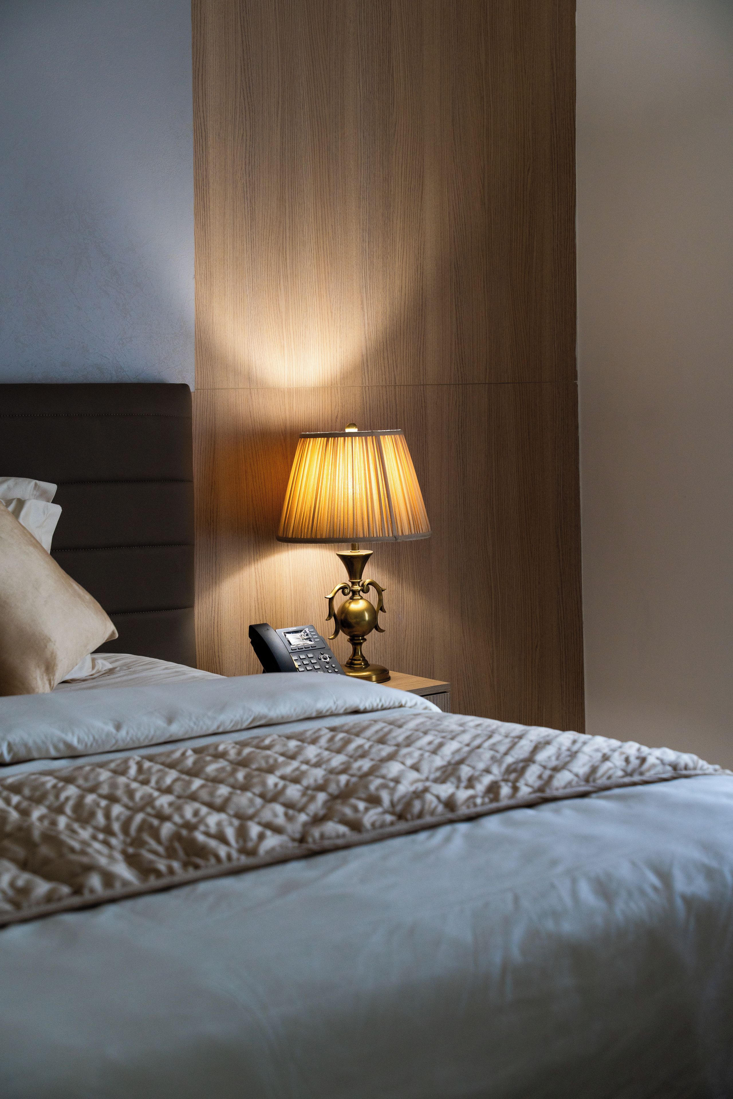 A hotel room with a bed, a bedside lamp, and a telephone.