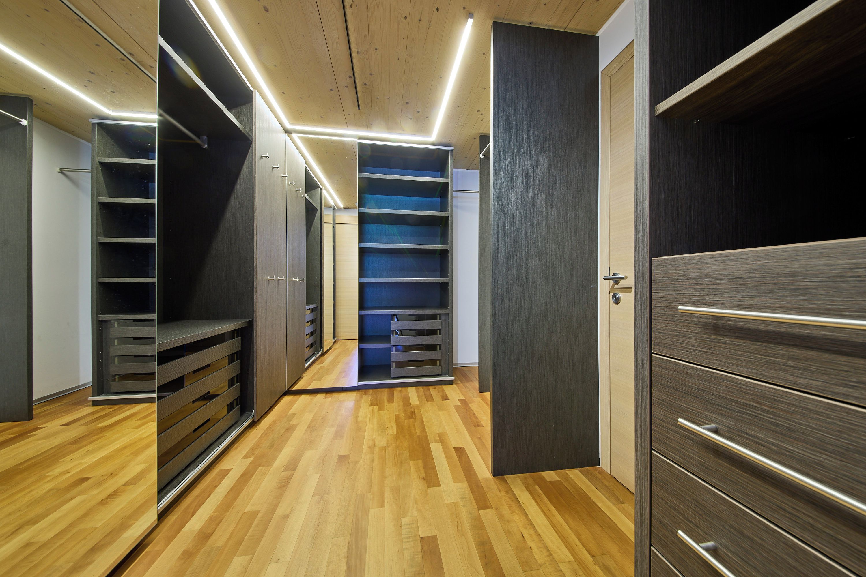 Een modern interieur met houten vloeren, inbouwplanken en een mix van open en gesloten deuren.
