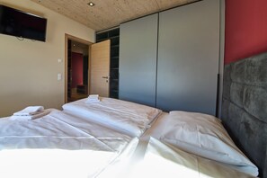 Ein Hotelzimmer mit einem Bett, einem Kleiderschrank und einem an der Wand befestigten Fernseher.