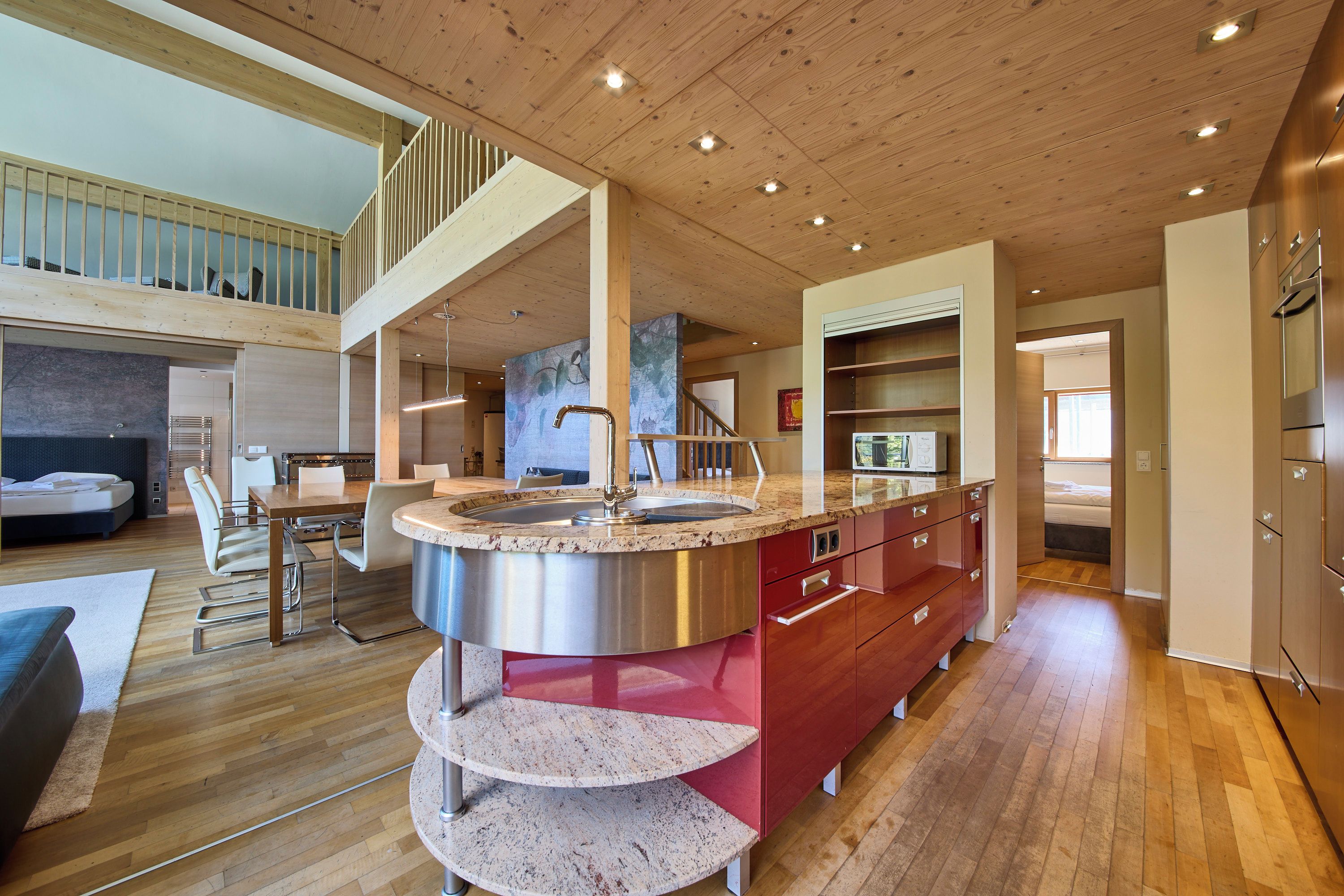 Een moderne keuken met een centraal eiland, houten vloeren en een entresol.