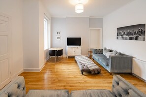 Un salon avec un canapé, un téléviseur, une table et un banc.