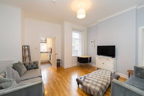 A modern living room with a sofa, a coffee table, and a television. - Cosy Kilmarnock Apartment (East Ayrshire Council)