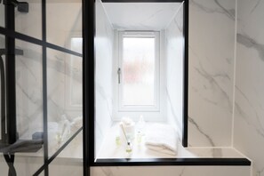 Une salle de bain avec un mur en marbre, une fenêtre et un porte-serviettes.