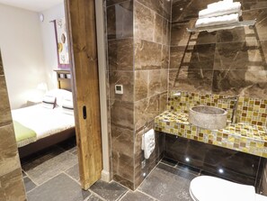 Ein Badezimmer mit Dusche, Toilette und einem Waschbecken mit Mosaikfliesen-Spritzschutz.