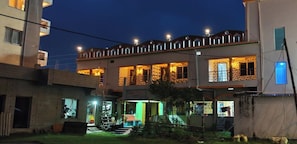 A multi-story building with a courtyard, featuring a staircase, a pool, and a well-lit entrance. - SINGHBHUM-The Shore (Kanthi)