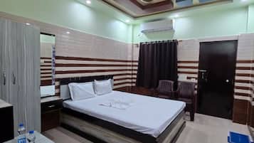 Habitación de hotel con cama, escritorio, armario y ventilador de techo.