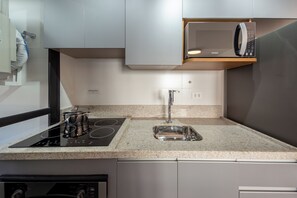 A modern kitchen with a built-in microwave, stainless steel appliances, and a granite countertop. - Agami by Bhomy  (São Paulo)