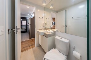 A modern bathroom with a toilet, sink, and mirror. - Agami by Bhomy  (São Paulo)