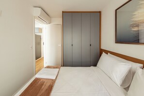 A hotel room with a bed, a wooden headboard, a grey wardrobe, and a painting on the wall. - Agami by Bhomy  (São Paulo)