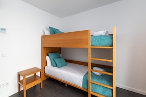A bunk bed with a wooden frame, a small wooden nightstand, and a single power outlet on the wall. - Vacation Villa 'Ereza Royal Family Hoopoe 117' with Private Pool, Wi-Fi and Air Conditioning (Playa Blanca)