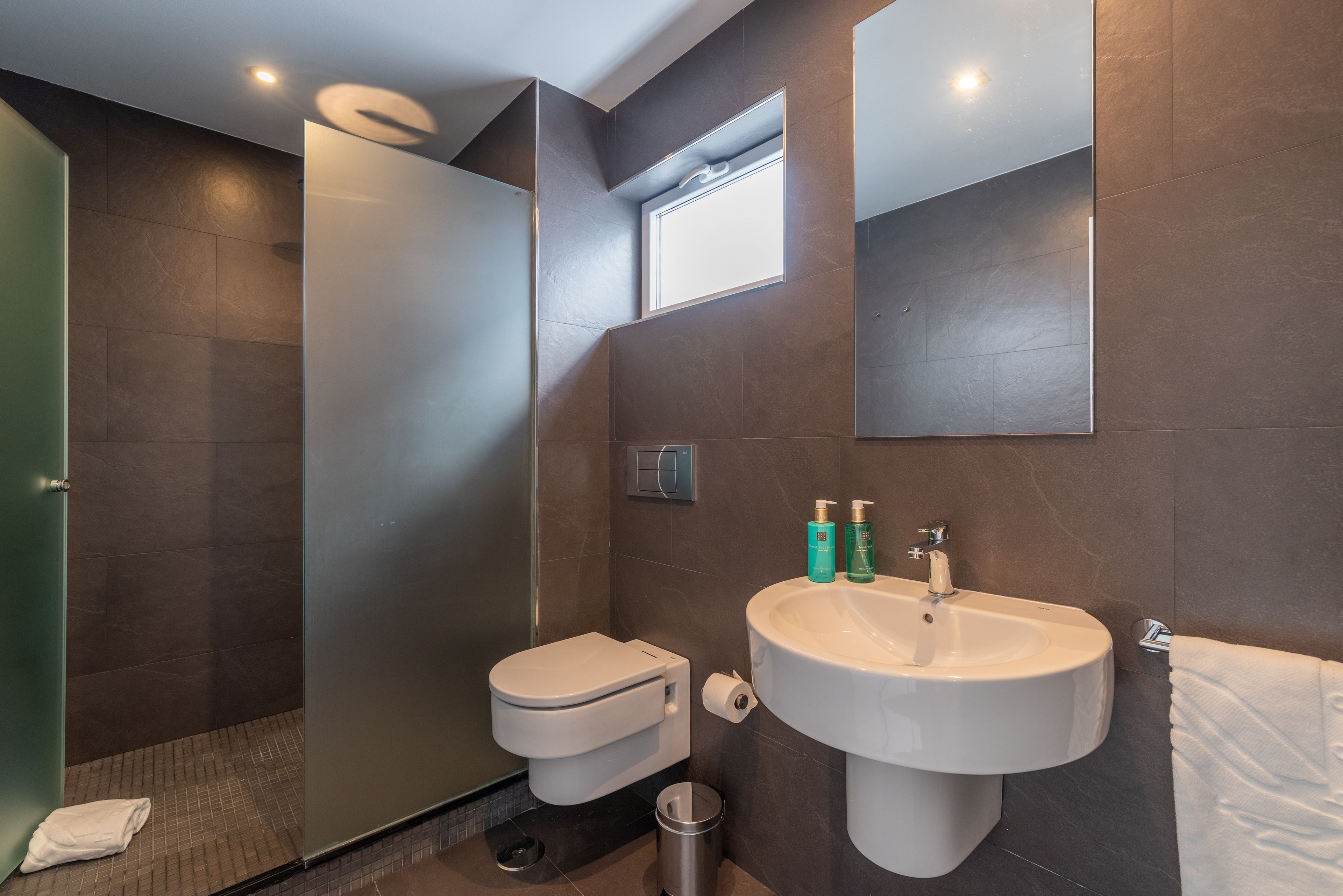 A modern bathroom with a toilet, sink, and shower.