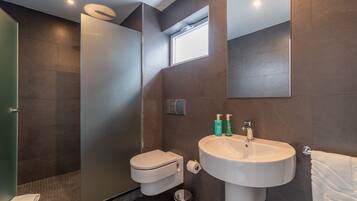 A modern bathroom with a toilet, sink, and shower.