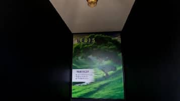 Een plafond met een decoratieve lamp en een wandgemonteerde beeldscherm waarop een natuurscène met tekst wordt getoond.