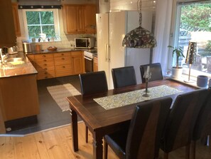 Eine Küche mit Holzschränken, einer Mikrowelle, einem Kühlschrank und einem Essbereich mit Tisch und Stühlen.