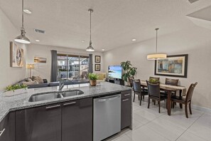 A modern kitchen with a central island, built-in dishwasher, and pendant lighting. - Serenity Resort | Private Pool Townhome | 3Bd3bath (Four Corners)
