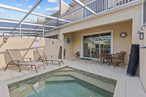 An indoor pool area with lounge chairs and a table, a glass door entrance, and a clock on the wall. - Serenity Resort | Private Pool Townhome | 3Bd3bath (Four Corners)
