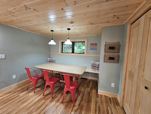 Un comedor con una mesa de madera y sillas rojas, una ventana con vistas y un letrero en la pared.