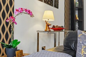 A modern living room with a potted orchid, a lamp, a bowl of pinecones, and a sofa. - Easy London Links | Tottenham Stadium | Drumsheds (Greater London)