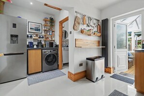 A compact kitchen with a washing machine, a coffee machine, and a refrigerator. - Easy London Links | Tottenham Stadium | Drumsheds (Greater London)