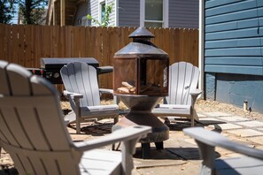 A backyard with a fire pit, outdoor seating, and a wooden fence.