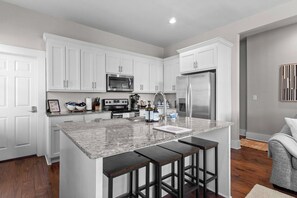 A modern kitchen with white cabinetry, stainless steel appliances, and a granite countertop.