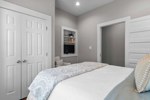 Ein Schlafzimmer mit einem Bett, einem Kleiderschrank, einer Ablagefläche mit Dekoration und einer Tür.
