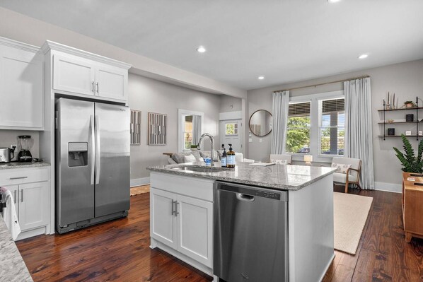 A modern kitchen with a stainless steel refrigerator, a built-in dishwasher, and a granite countertop.