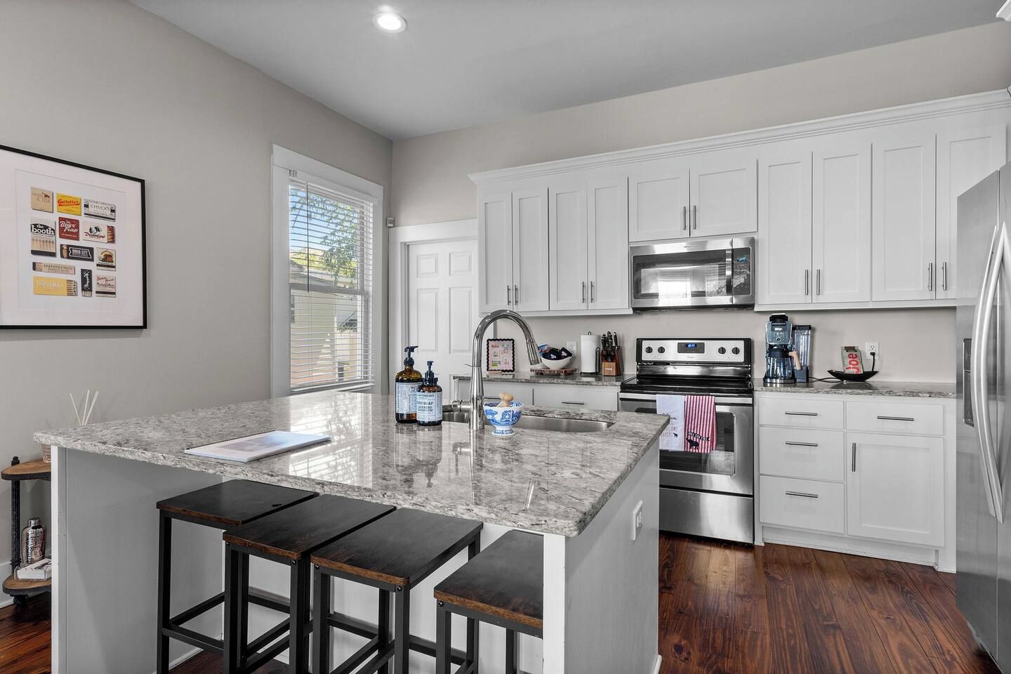 A modern kitchen with white cabinets, stainless steel appliances, and a granite countertop.