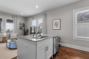 A modern kitchen with a built-in island, stainless steel appliances, and a large window with blinds.