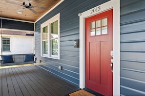 A porch with a swing, a red door, and a mailbox.