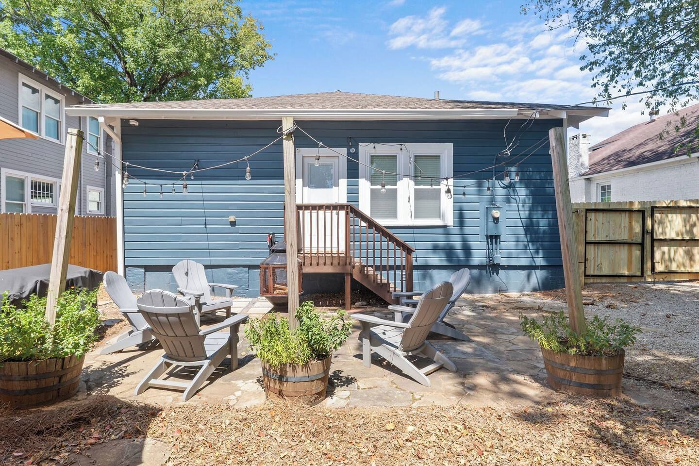 Ein blaues Haus mit überdachter Terrasse, Holzdeck und Gartenmöbeln.