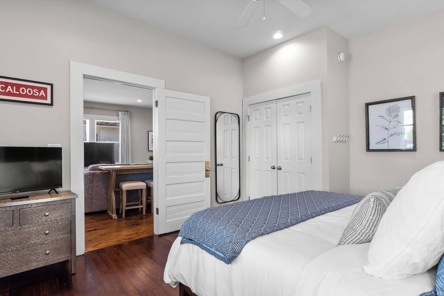 A bedroom with a bed, a TV, a desk, and a wardrobe.