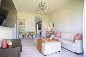 A modern living room with a sofa, coffee table, and a dining area with chairs.