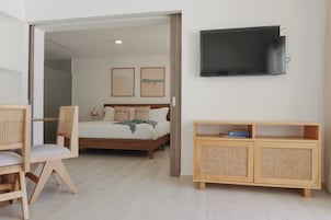 A bedroom with a bed, a TV mounted on the wall, a wooden cabinet, and a chair.