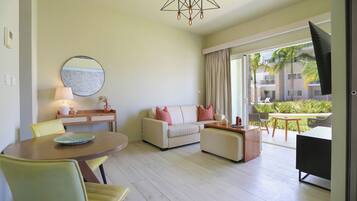 A modern living room with a sofa, chairs, a dining table, and a large window with a view of a building and greenery.