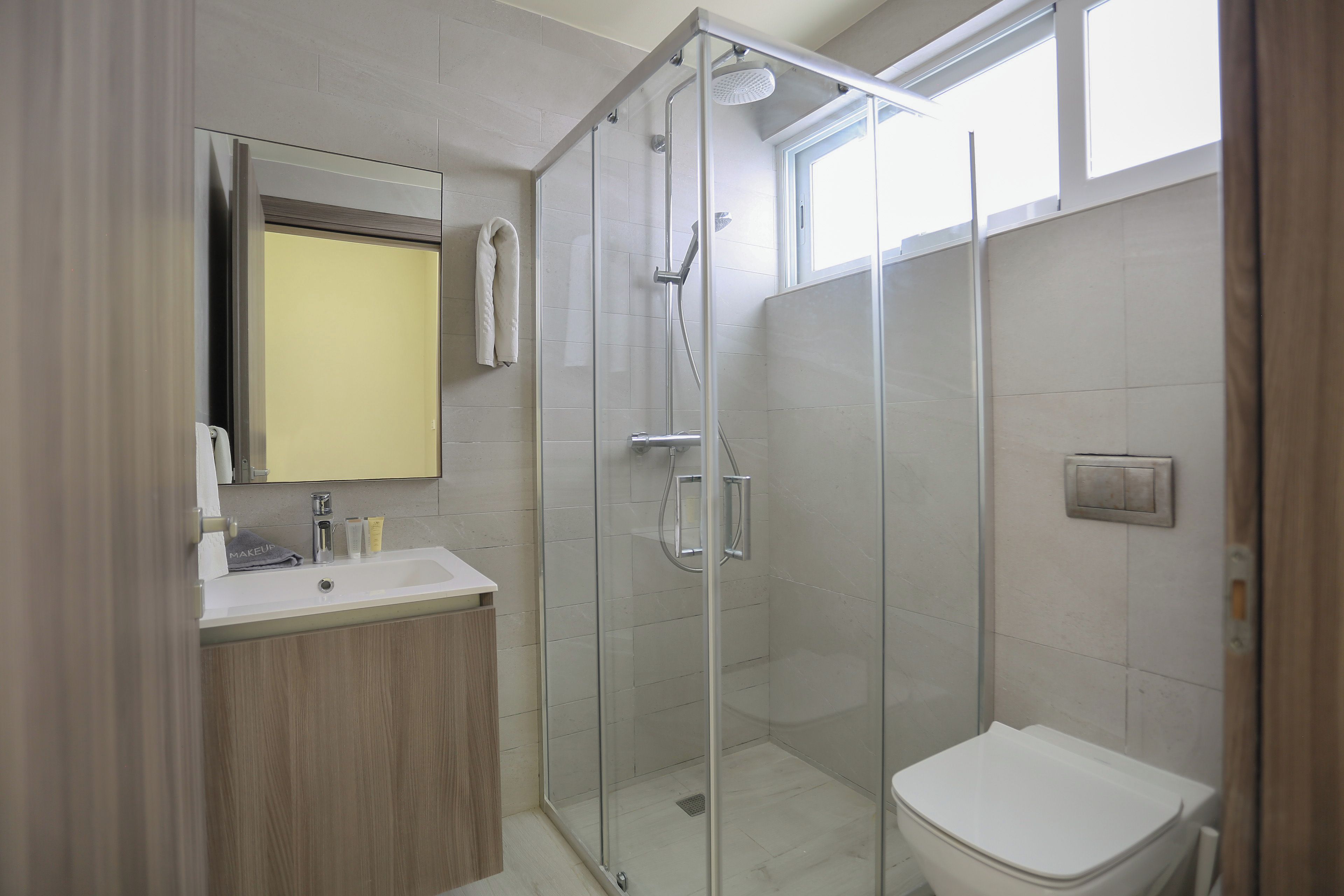 A modern bathroom with a glass-enclosed shower, a white sink, and a toilet.