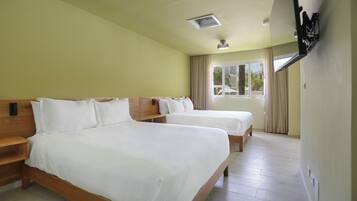 Habitación de hotel con dos camas, cabeceros de madera, una ventana con cortinas y un ventilador de techo.