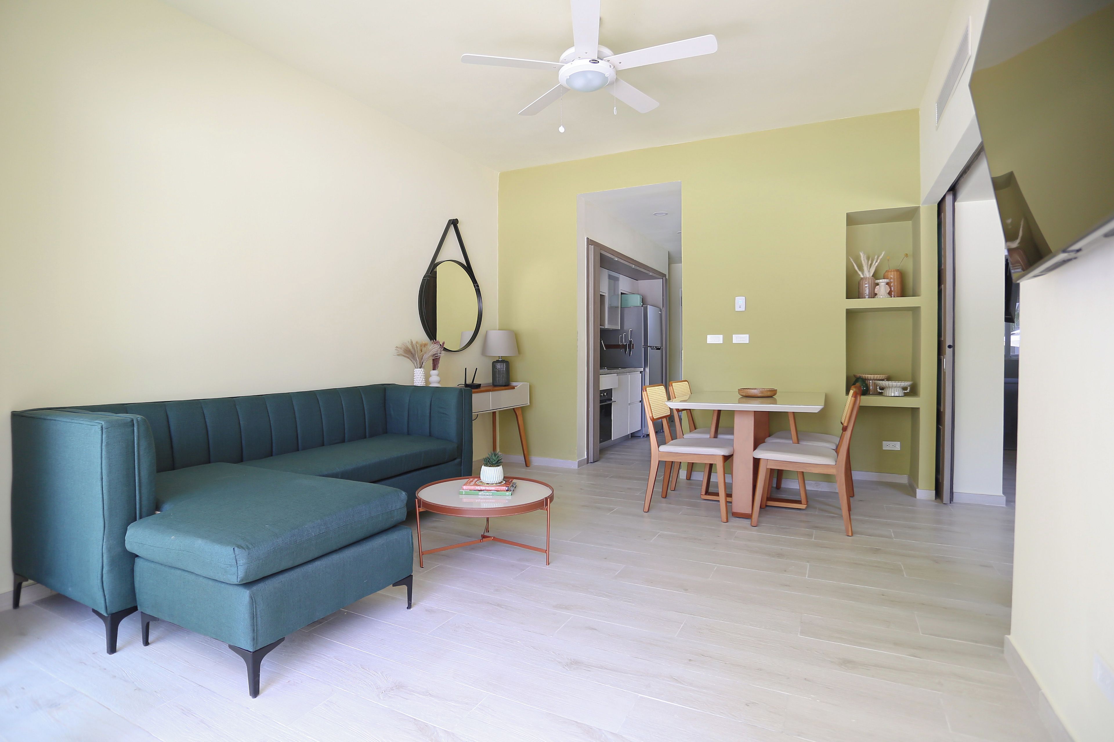 Ein Wohnzimmer mit einer Couch, einem kleinen runden Tisch und einem Essbereich mit Stühlen.