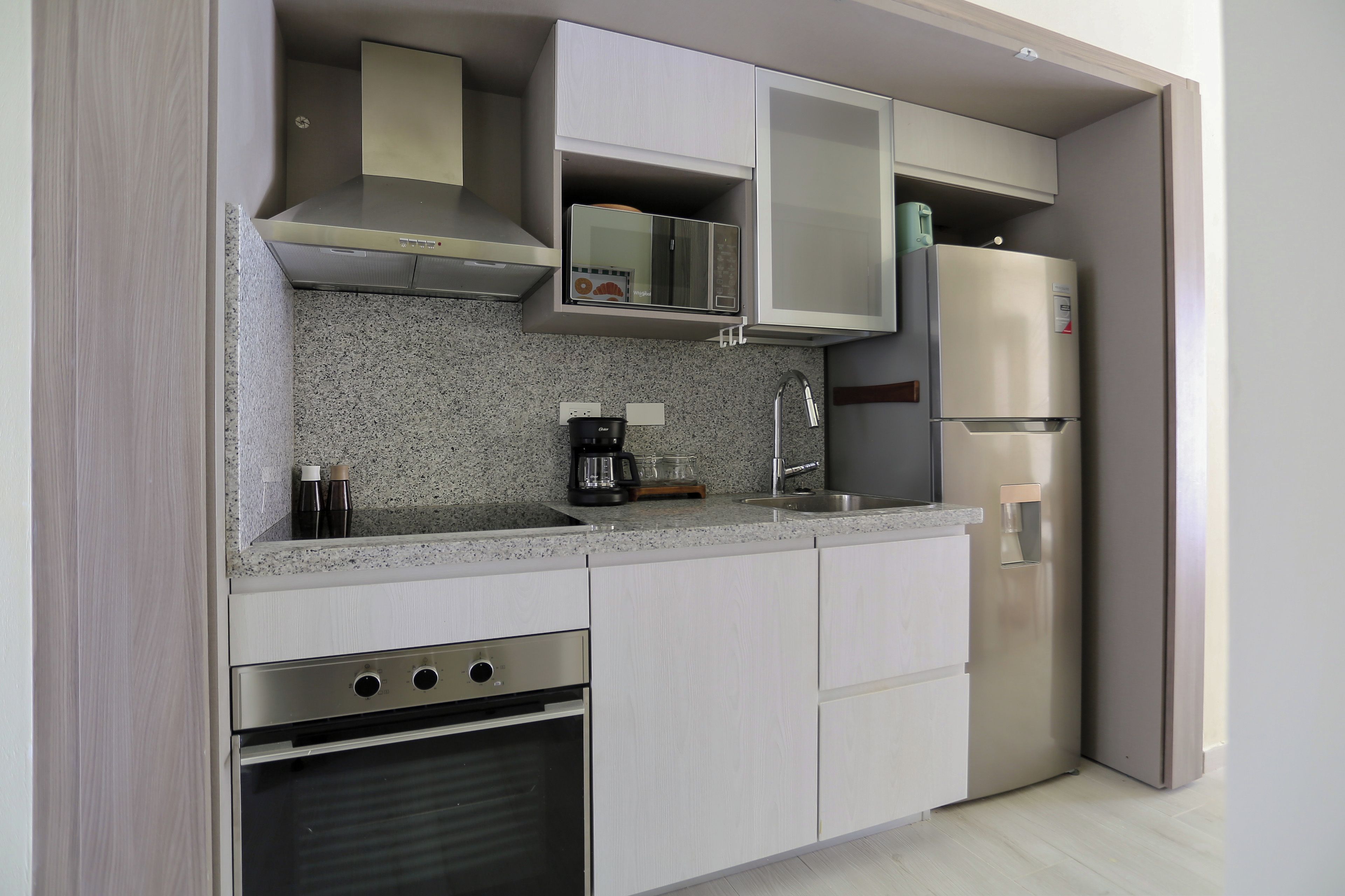 A modern kitchen with stainless steel appliances, a granite countertop, and white cabinetry.