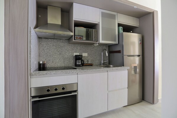 A modern kitchen with stainless steel appliances, a granite countertop, and white cabinetry.