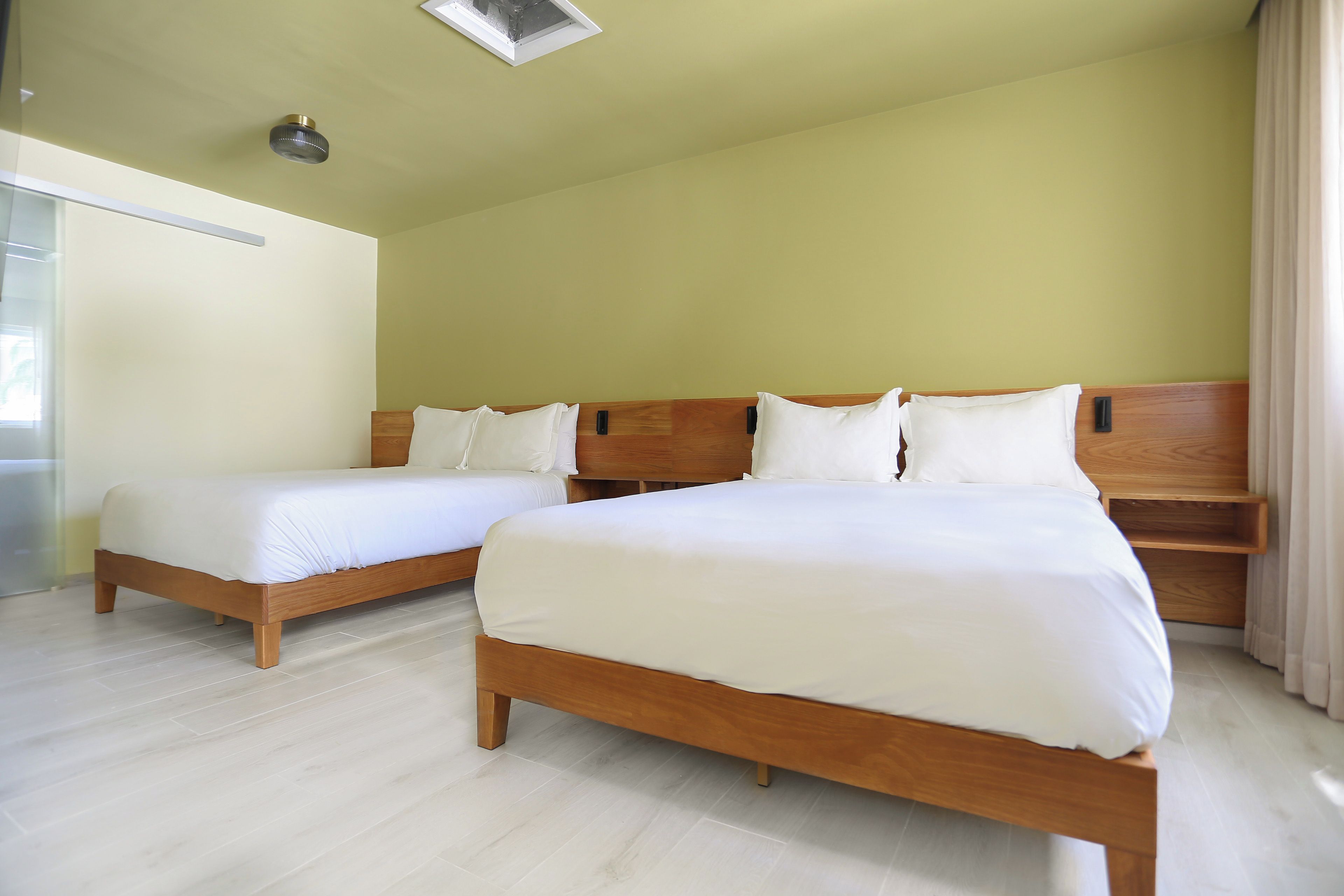 Una habitación de hotel con dos camas de madera, cabeceros de madera y suelo de color claro.