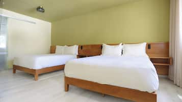 Une chambre d’hôtel avec deux lits en bois, une tête de lit en bois et un plancher de couleur claire.