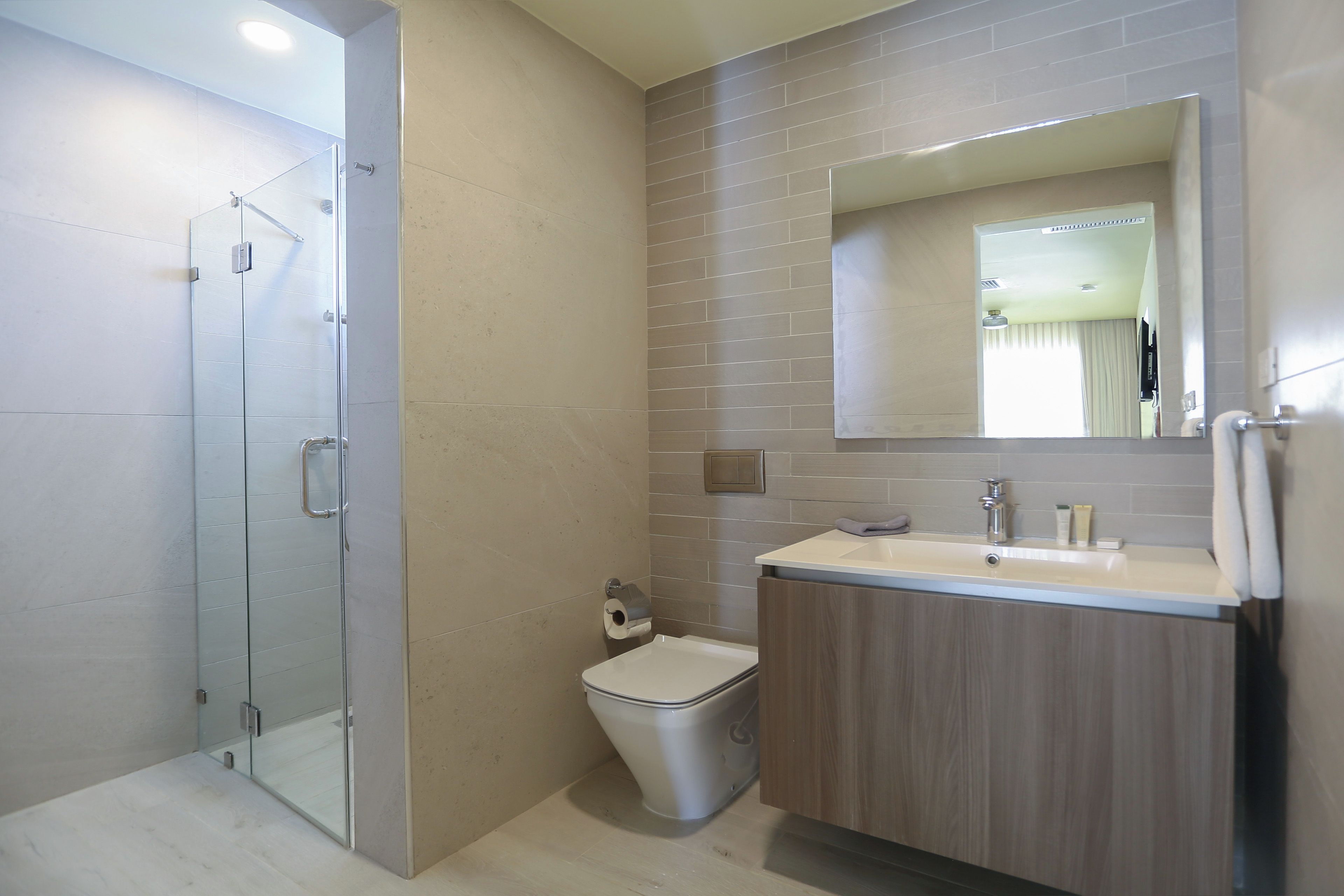 Un baño moderno con cabina de ducha de vidrio, inodoro y tocador con espejo.